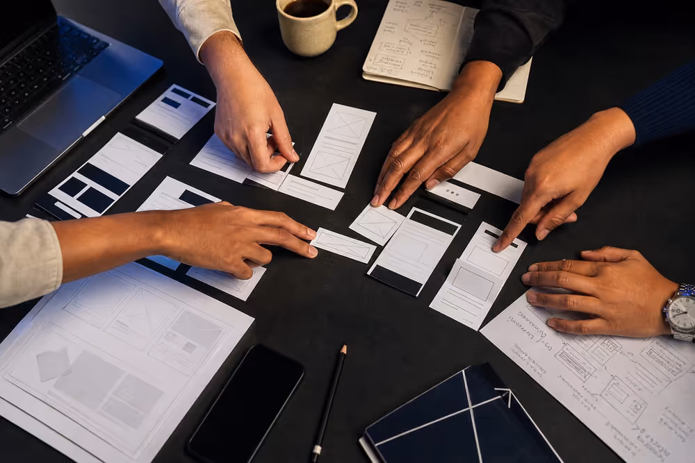 Hands arranging website wireframes during a strategy workshop